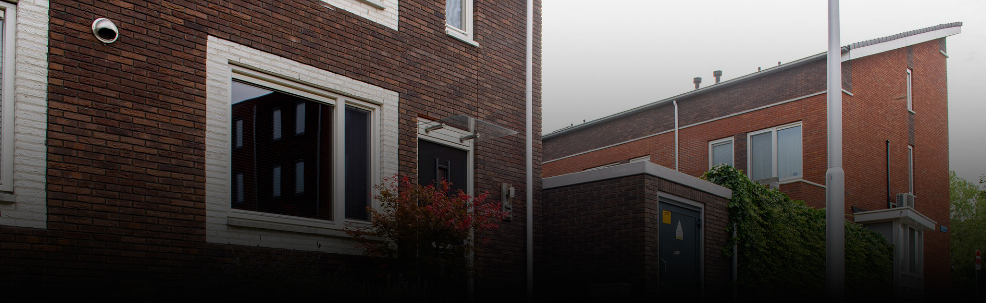 Voorkant van een huis met ernaast een transformatorhuisje