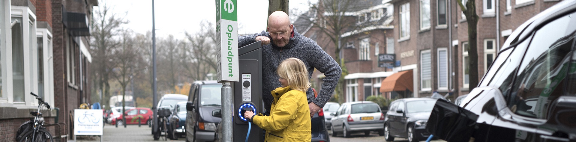 Meisje en man bij een laadpaal voor elektrische auto's