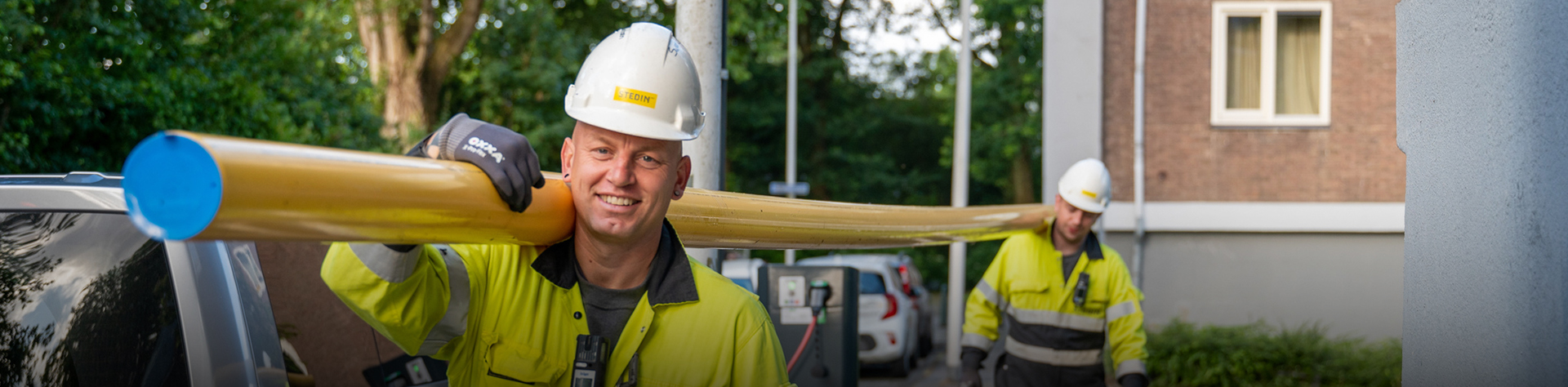 Monteurs lopen met een gasbuis door een woonwijk