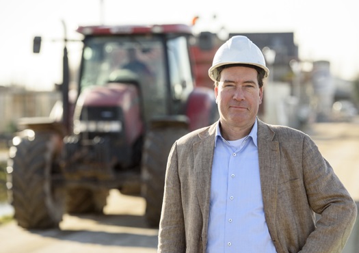 Man met bouwhelm op de achtergrond staat een tractor