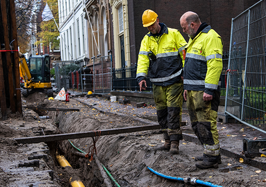 Monteurs van Stedin zijn aan het werk in een straat die open ligt waardoor de kabel zichtbaar zijn
