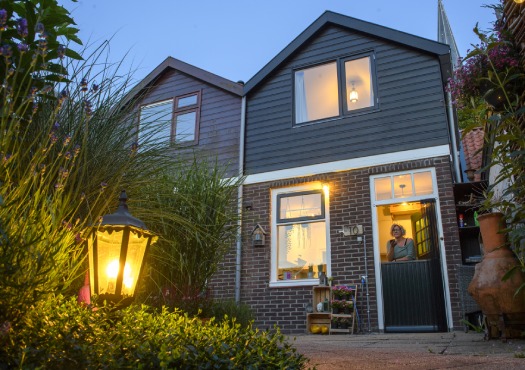 Verlichte woning met de bewoonster in de deuropening