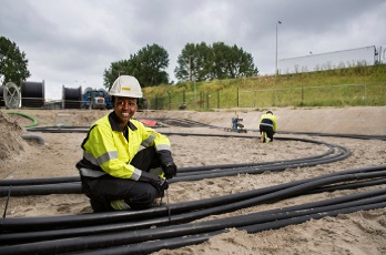 Stedin-monteur zit bij elektriciteitskabels in zandbed