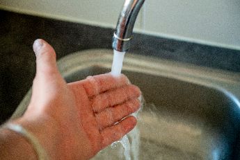 Hand onder water uit kraan